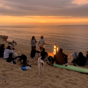 un grupo de personas sentadas alrededor de un fuego en la playa en traditional taghazout surf en Taghazout