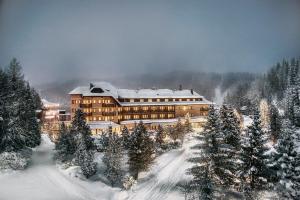a large building in the snow with snow covered trees at Hotel Hochschober in Turracher Hohe