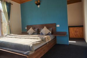 een slaapkamer met een bed met een blauwe muur bij Hostelgia in Manāli