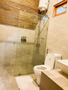 a bathroom with a shower and a toilet and a sink at Eco Bliss Cottages - Thanamalwila in Nikawewa
