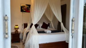 um quarto com uma cama de dossel com cortinas brancas em Dewangga Mountain View em Bangli