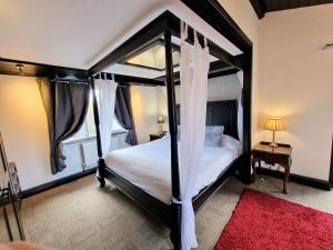 a bedroom with a four poster bed with a red rug at Ochil 9 with Private Hot Tub - Fife - Loch Leven - Lomond Hills - Pet Friendly in Kelty