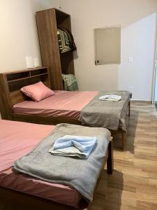 two beds in a room with towels on them at Ribas Pousada e Camping in Carambeí