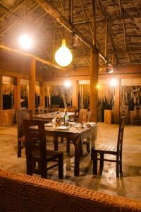 uma sala de jantar com mesa, cadeiras e luzes em Eco Bliss Cottages - Thanamalwila 