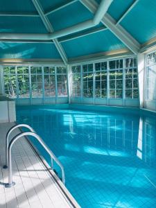 an indoor swimming pool with blue tile floors and windows at Landgoedhotel Villa Vennendal in Nunspeet