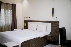 a bedroom with a large white bed and a chair at MO-House Hotels and Apartments Mabushi in Abuja