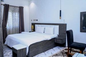 a bedroom with a large bed and a chair at MO-House Hotels and Apartments Mabushi in Abuja