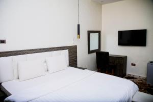 a bedroom with a large white bed and a chair at MO-House Hotels and Apartments Mabushi in Abuja