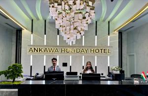 un hombre y una mujer sentados en un escritorio en un hotel vacacional amazónico en Ankawa Holiday Hotel en Erbil