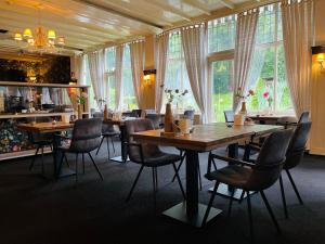 - une salle à manger avec des tables, des chaises et des fenêtres dans l'établissement Landgoedhotel Villa Vennendal, à Nunspeet