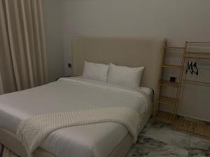 a bed with white sheets and pillows in a room at استديو راقي بالبوليفارد104 Boulevard Jar in Riyadh
