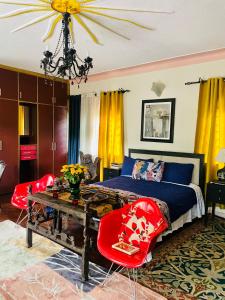 um quarto com uma cama, uma mesa e cadeiras em Casa de Roy em Kampala