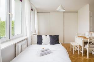 a white bedroom with a bed and a table at Urbanistów Cosy Studio in Warsaw