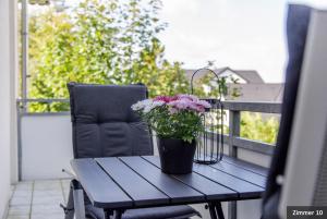 a wooden table with a potted plant on a balcony at Hotel See-Villa in Malente