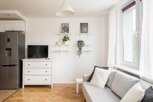 a white living room with a couch and a refrigerator at Urbanistów Cosy Studio in Warsaw