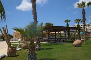 a palm tree in a park with a pavilion at Grand Blue Beach Hotel in Kardamaina