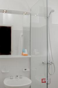 uma casa de banho branca com um lavatório e um chuveiro em Grand Hotel em San Fernando del Valle de Catamarca