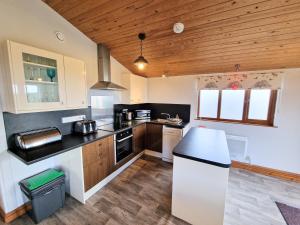 eine Küche mit schwarzen Arbeitsplatten und Holzdecken in der Unterkunft Ochil 8 with Private Hot Tub - Fife - Loch Leven - Lomond Hills in Kelty