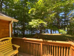 un banco sentado en un porche con vistas al agua en Ada Lake Cottage - Port Carling couples retreat, en Port Carling