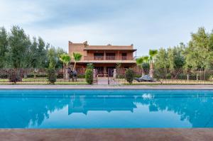 a house with a swimming pool in front of a house at Ferme Sidi Safou & Spa in Marrakesh