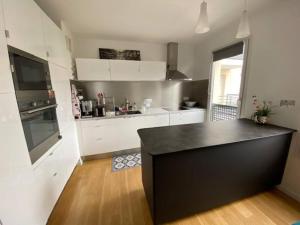 een keuken met witte kasten en een zwart aanrecht bij Appartement de standing calme idéal pour les JO ! in Suresnes