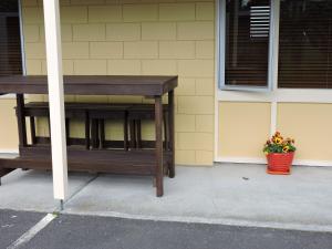 a wooden table sitting outside of a building with a pot of flowers at Maple Lodge Motel in Matamata