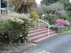 a set of stairs with pink flowers and trees at Maple Lodge Motel in Matamata