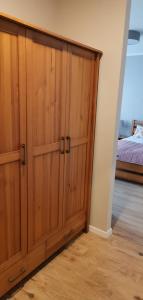 - une grande armoire en bois dans une chambre avec un lit dans l'établissement Apartamenty Po Kominiarzach I, à Chełmno