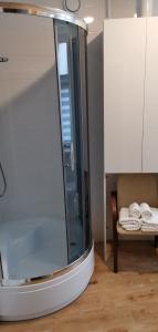 ein Badezimmer mit einer Glasdusche und einer Bank mit Handtüchern in der Unterkunft Apartamenty Po Kominiarzach in Chełmno