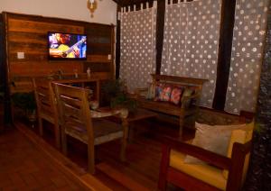 uma sala de estar com cadeiras e uma televisão na parede em Pousada Toque Mineiro em Tiradentes