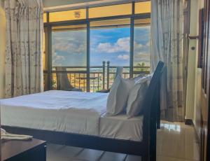 a bedroom with a bed and a large window at Vinetea Hotel in Kampala