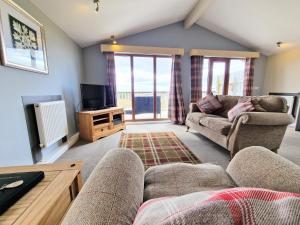 a living room with a couch and a tv at Ochil 10 with Private Hot Tub - Fife - Loch Leven - Lomond Hills in Kelty