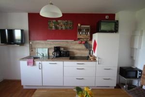 a kitchen with white cabinets and a red wall at Hof Lebenslust für Mensch und Tier in Lautrach