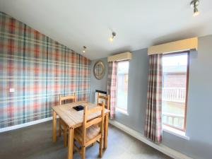a dining room with a wooden table and two windows at Ochil 10 with Private Hot Tub - Fife - Loch Leven - Lomond Hills in Kelty
