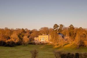 a large yellow house in the middle of a field at Ponsbourne Park in Hertford