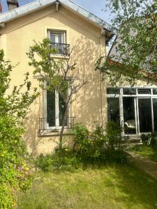 une maison jaune avec un arbre devant elle dans l'établissement Maison proche Paris, à Colombes