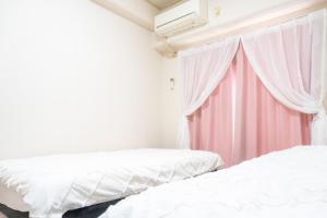 2 camas en una habitación con cortina rosa en coco eleele 901, en Osaka