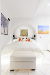a white bedroom with a white bed with an ottoman at Aiolos luxury in the centre of plaka in Athens