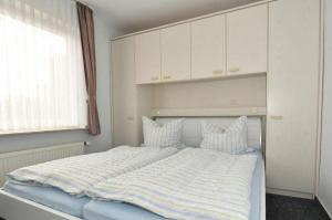 Una cama con una manta a rayas en un dormitorio en Ferienwohnung-Eilts-Whg-10, en Borkum