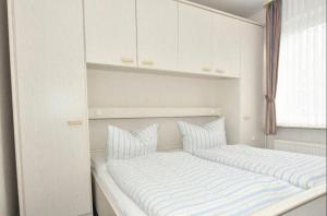Un dormitorio con una cama con almohadas a rayas y una ventana en Ferienwohnung-Eilts-Whg-10, en Borkum