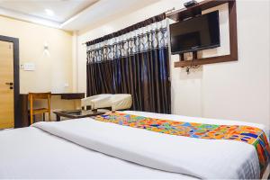 a hotel room with a bed and a flat screen tv at FabHotel Krishna Regency in Pune