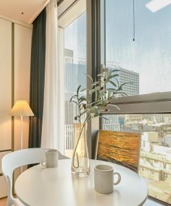 a vase with flowers on a table in front of a window at Seoul COMOCASA Fully Furnished Studio in Seoul