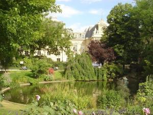 a garden with a pond in front of a building at La Belle Du Marais in Paris