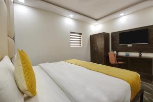 een slaapkamer met een bed, een bureau en een televisie bij Hotel The Eden Park in Noida