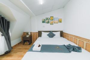 um quarto com uma cama branca e um cobertor azul em AN TÂM House Đà Lạt em Da Lat