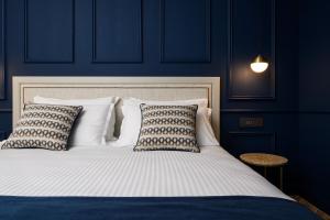 ein blaues Schlafzimmer mit einem weißen Bett mit Kissen in der Unterkunft XVI Suites - Adults Only in Naxxar