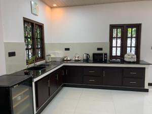 a large kitchen with black counter tops and windows at Leena Holiday Home in Batticaloa