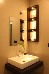 La salle de bains est pourvue d'un lavabo blanc et d'un miroir. dans l'établissement Leena Holiday Home, à Batticaloa