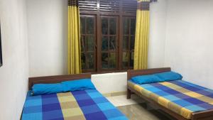 two beds in a room with a window at Henas Revrstone Holiday in in Matale