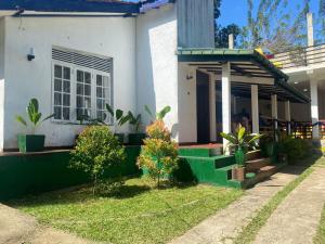 una casa blanca con porche y algunas plantas en Henas Revrstone Holiday in, en Matale